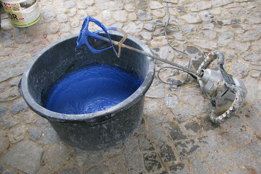Handwerkliche Herstellung eines Kalkputzes: Mit dem elektrischen Handrührgerät wird blaues Pigment mit Sumpfkalk vermischt.