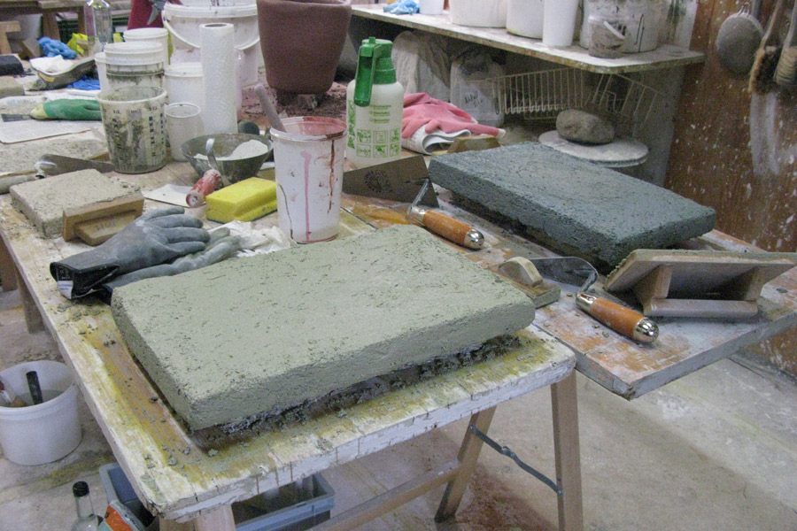 Handwerkliche Herstellung eines Tadelakt-Musters: Auf einer Musterplatte aufgetragener Kalkputz