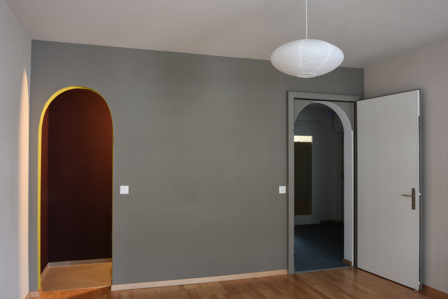 Farbgestaltung Praxisraum: Das Bild zeigt die Eingangswand mit offener Tür, so dass die Gestaltung des Türbogens sichtbar wird.